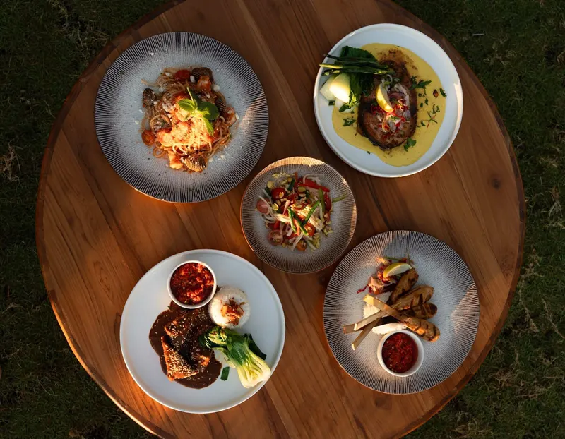 Five small plates from the Saga kitchen on a round wooden table, seen from above